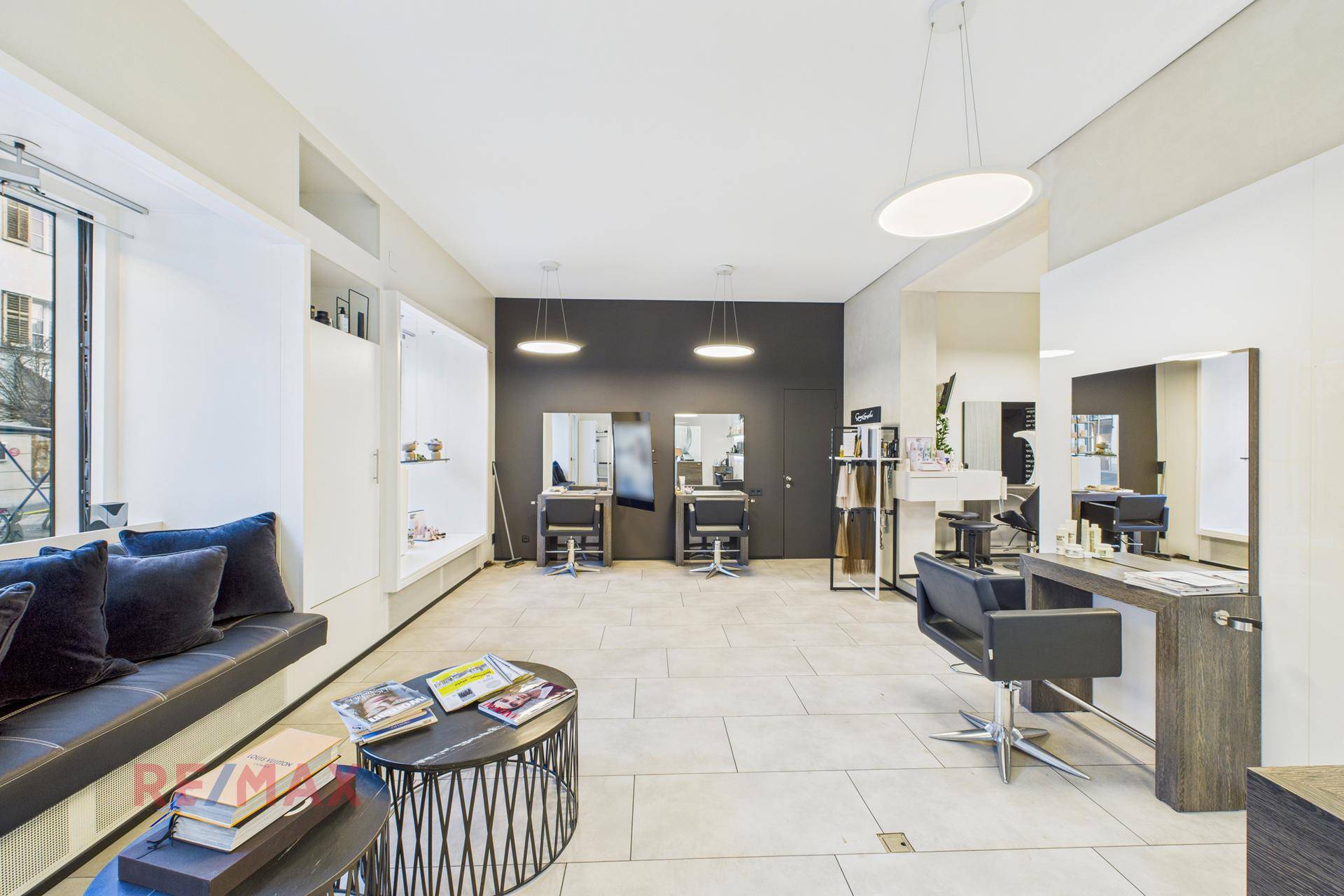 Heller Salonbereich mit Sitzgelegenheiten, dunklen Wänden und modernen Fliesenböden.
