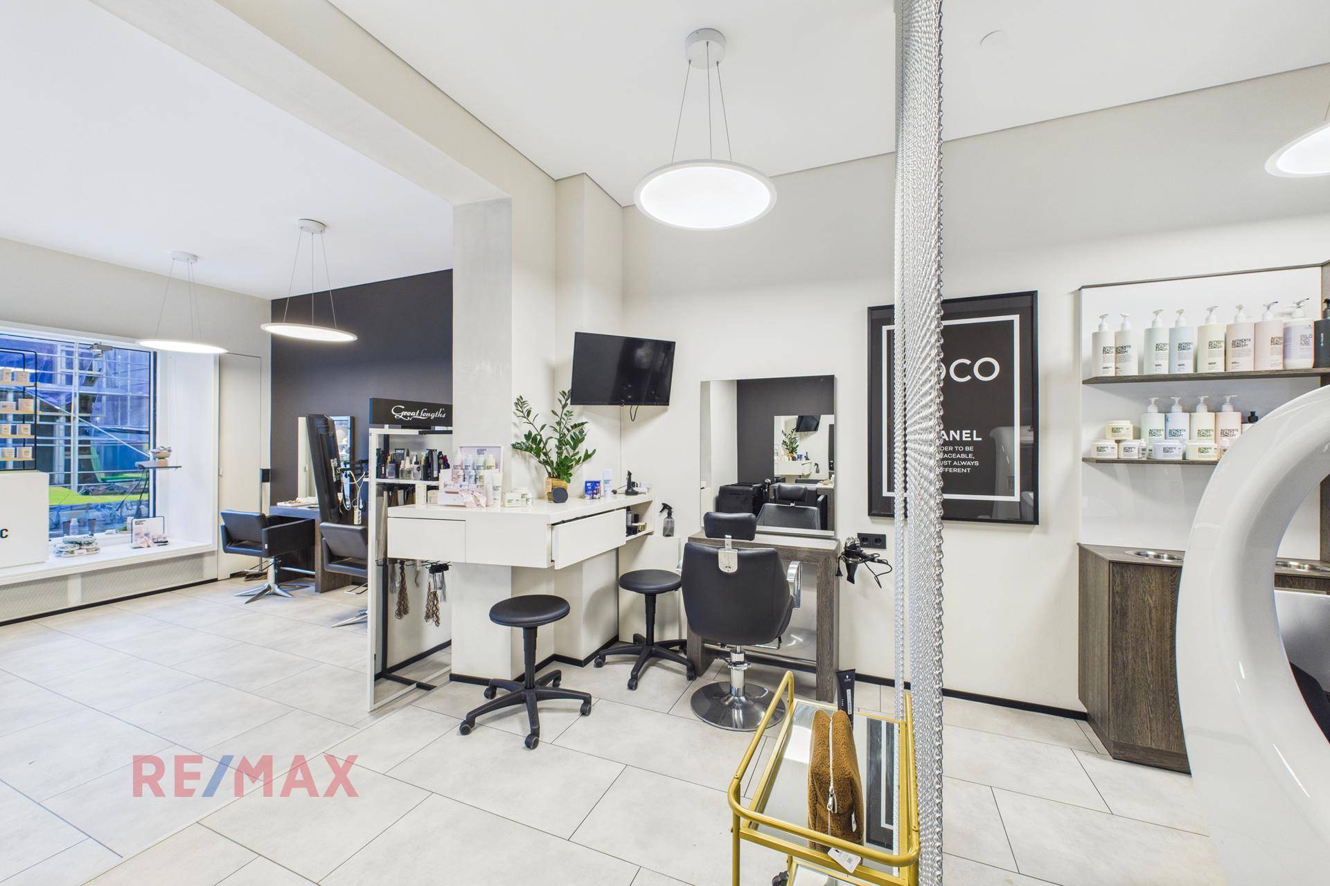 Styling-Bereich in einem modernen Salon mit Spiegeln, Arbeitsplätzen und Fliesenboden.