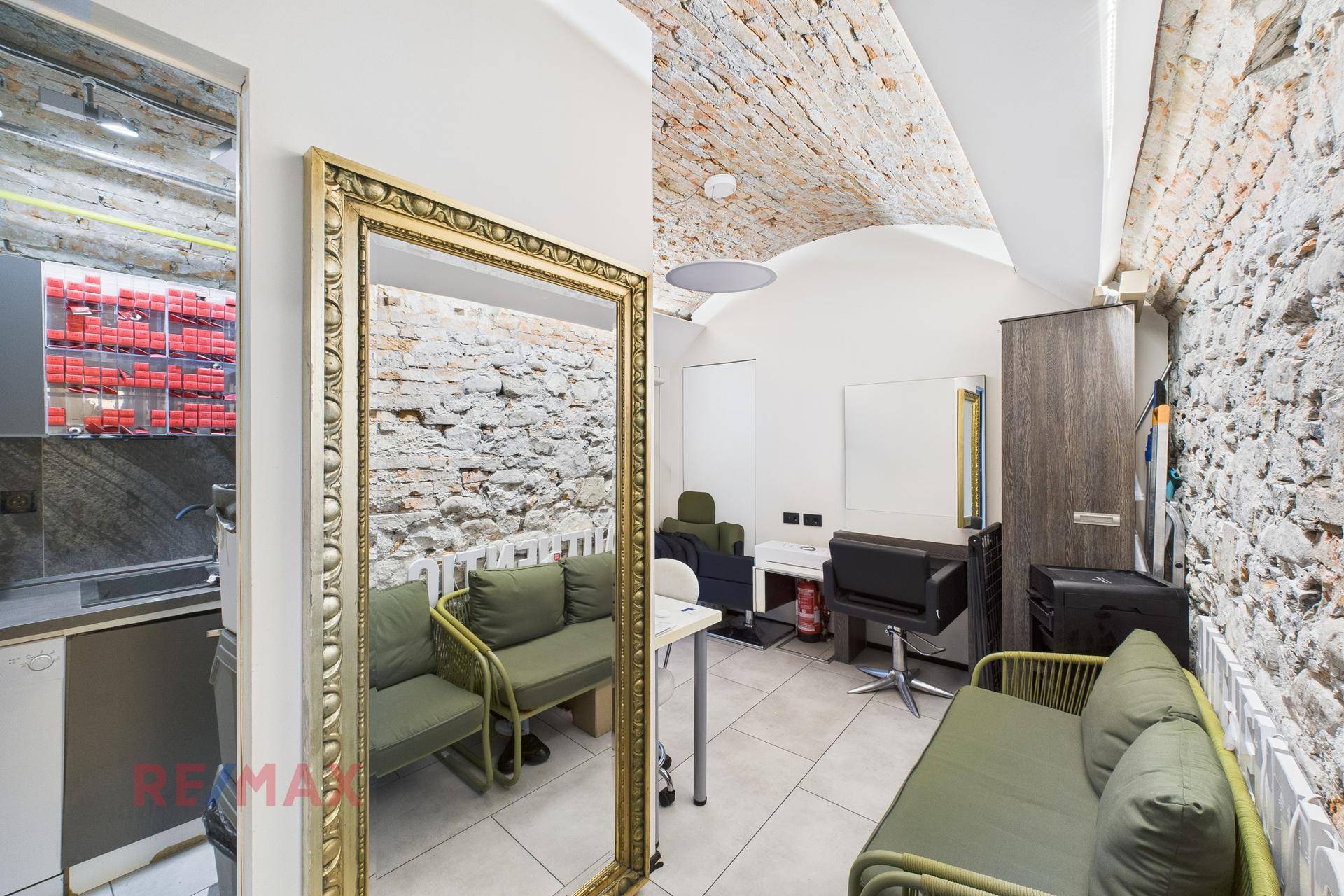 Hinterer Bereich des Salons mit freigelegten Ziegelwänden, Gewölbedecke und Sitzgelegenheiten.