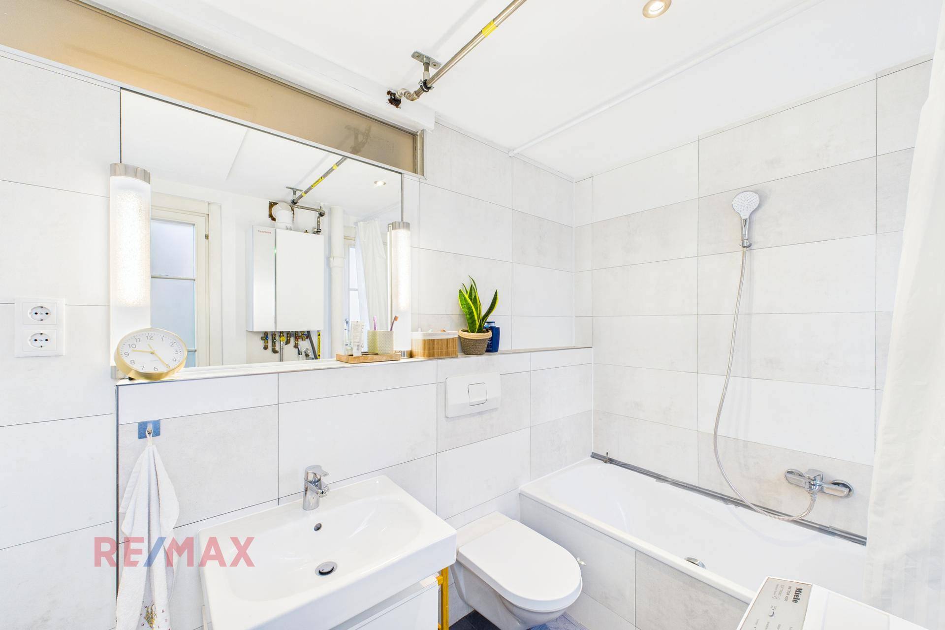Modernes Badezimmer mit Badewanne, Waschbecken, Spiegel und weißen Fliesen.
