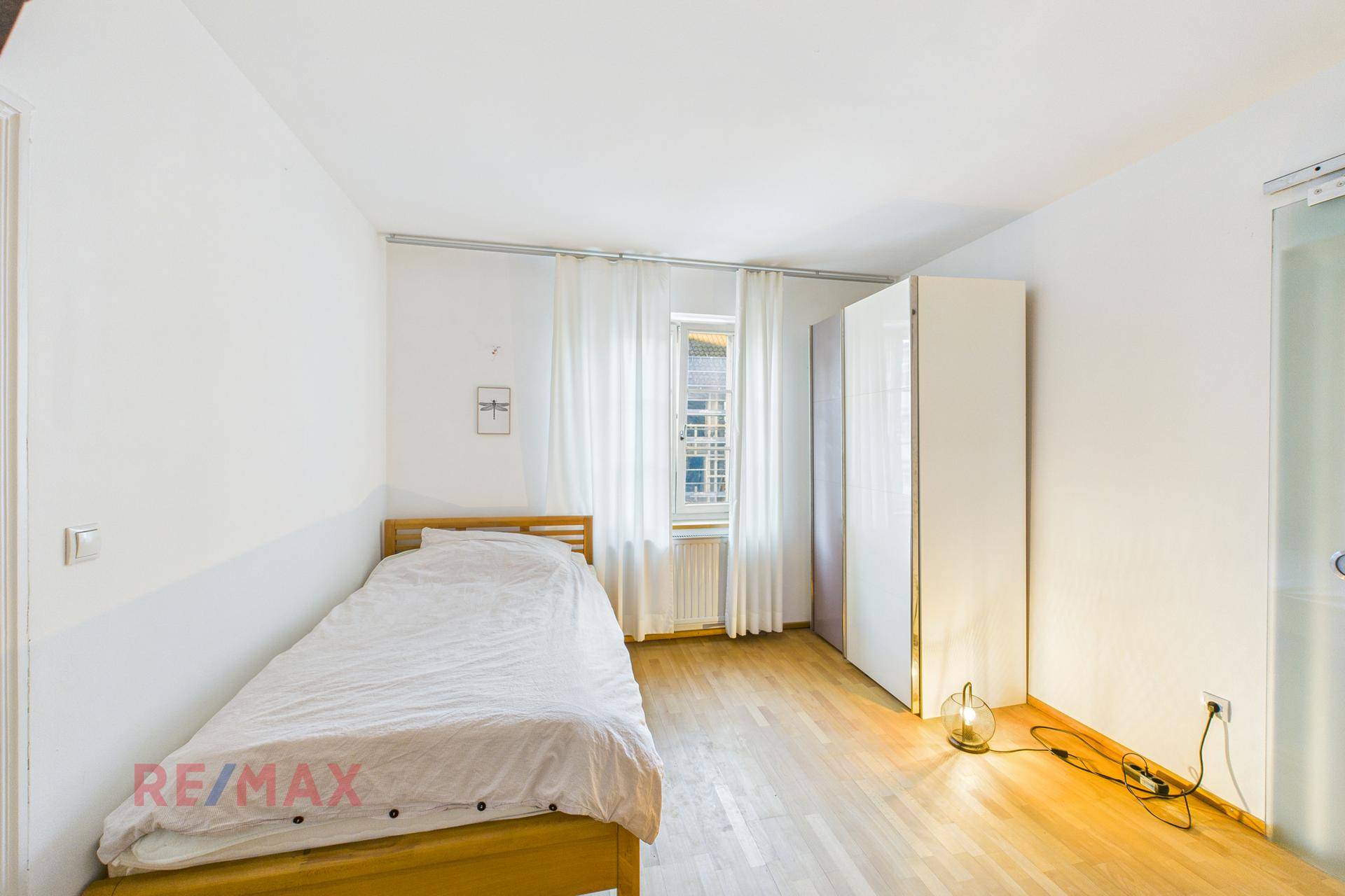 Gemütliches Schlafzimmer mit Einzelbett, Kleiderschrank und Parkettboden, hell und freundlich.