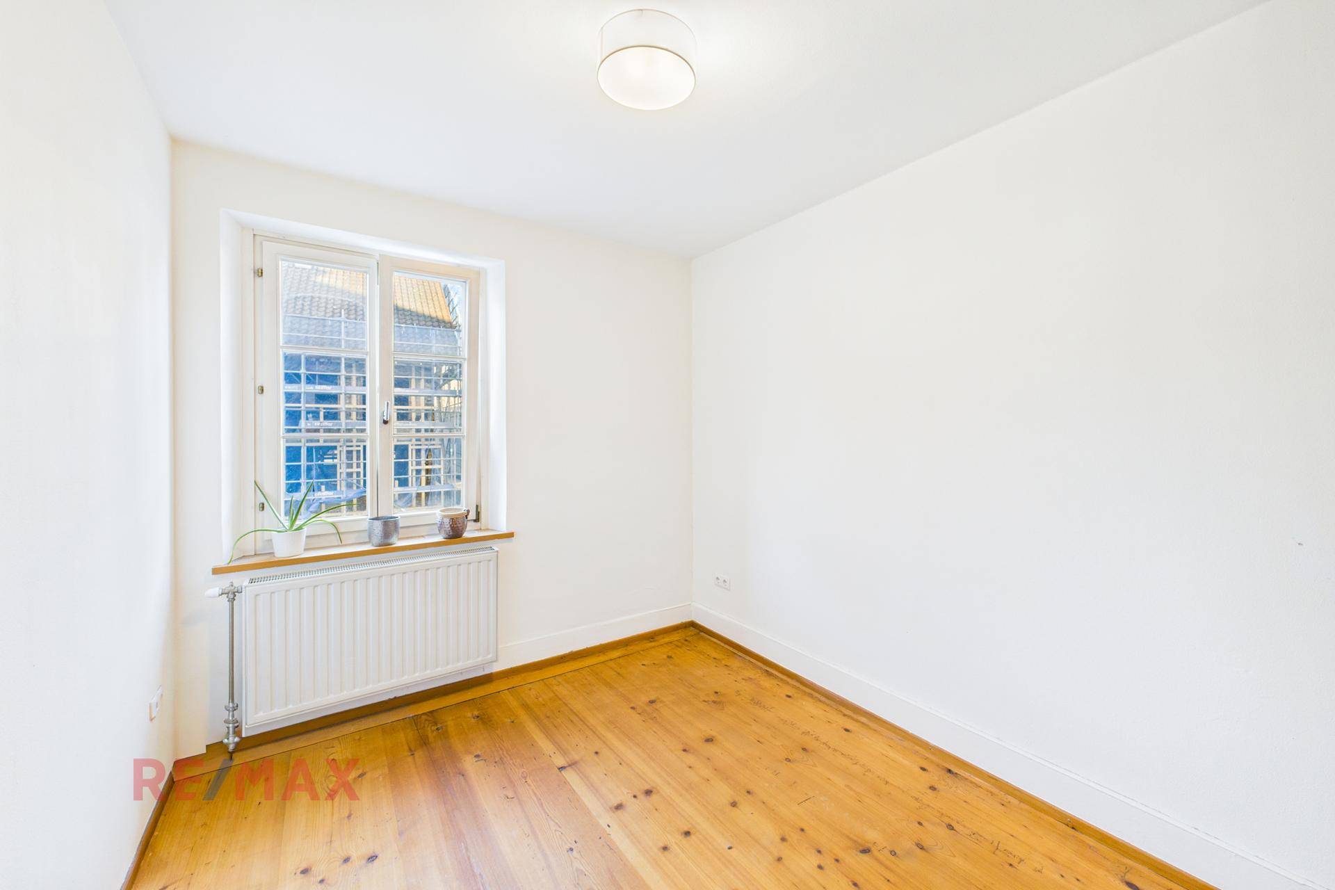 Leeres Schlafzimmer mit Holzboden und großem Fenster, bereit für individuelle Gestaltung.