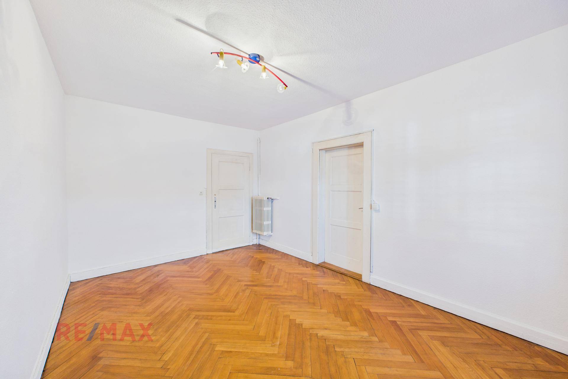 Lichtdurchflutetes Wohnzimmer mit Fischgrätparkett und Fenster, einladend und hell.