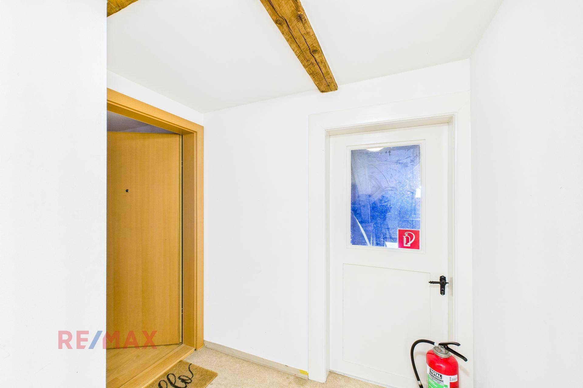 Heller Flur mit Holzbalken und Türen, mit Feuerlöscher für die Sicherheit.