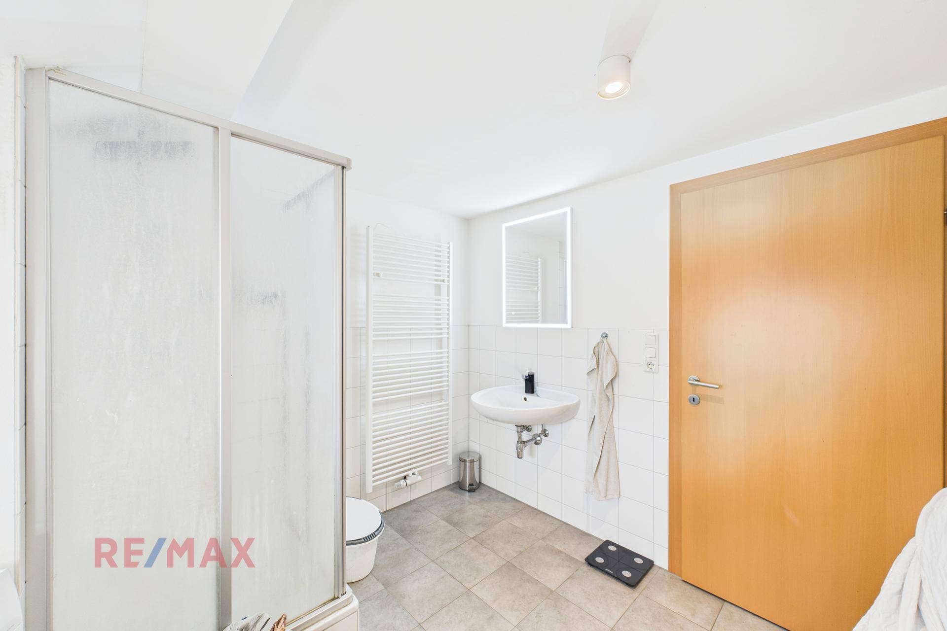 Modernes Badezimmer mit Duschkabine, WC, Waschbecken und beheiztem Handtuchhalter.