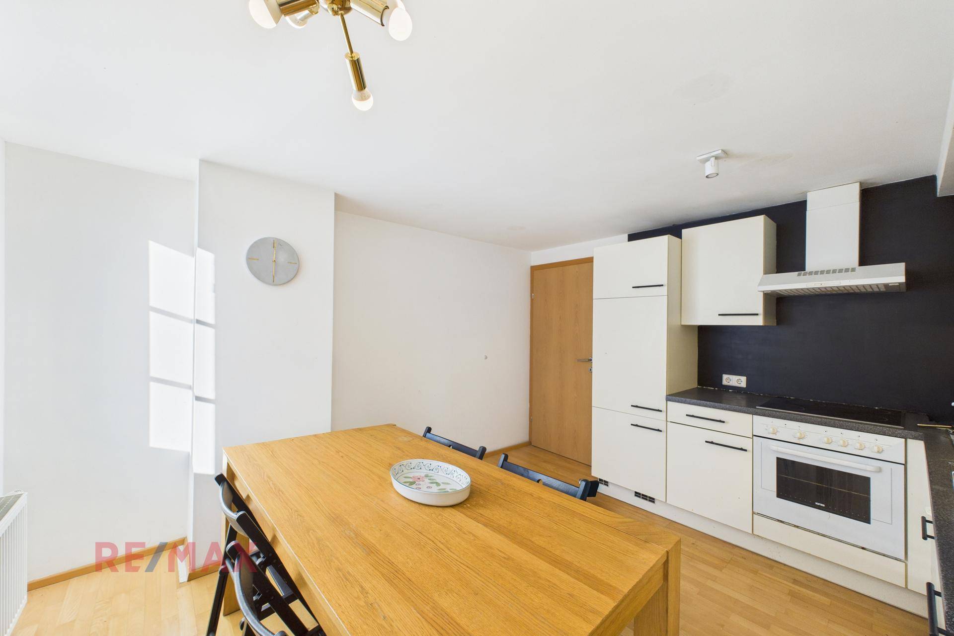 Heller Essbereich in der Küche mit Holztisch und modernen Hängelampen.