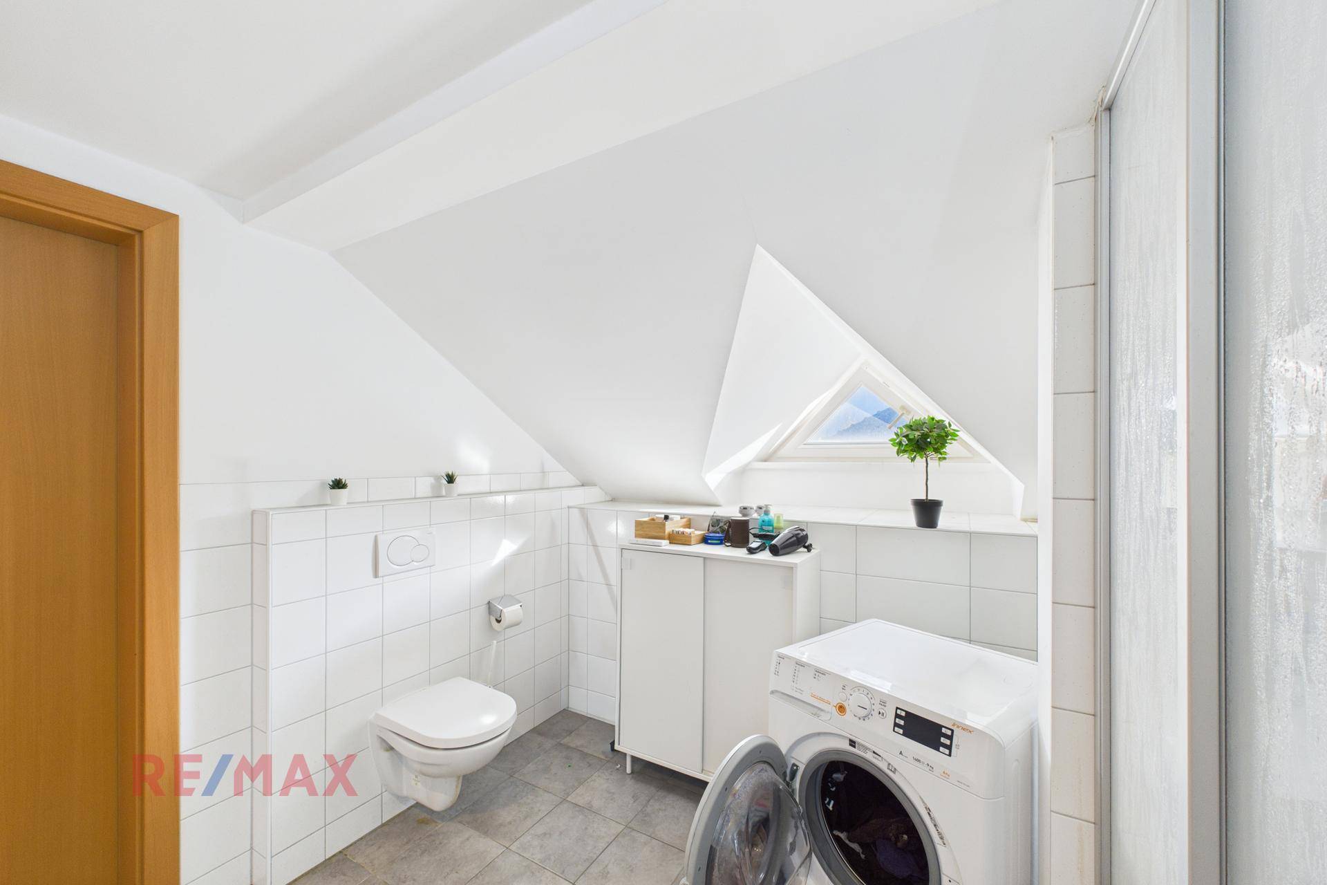 Modernes Badezimmer im Dachgeschoss mit Schrägdach, Waschmaschine und Dachfenster.