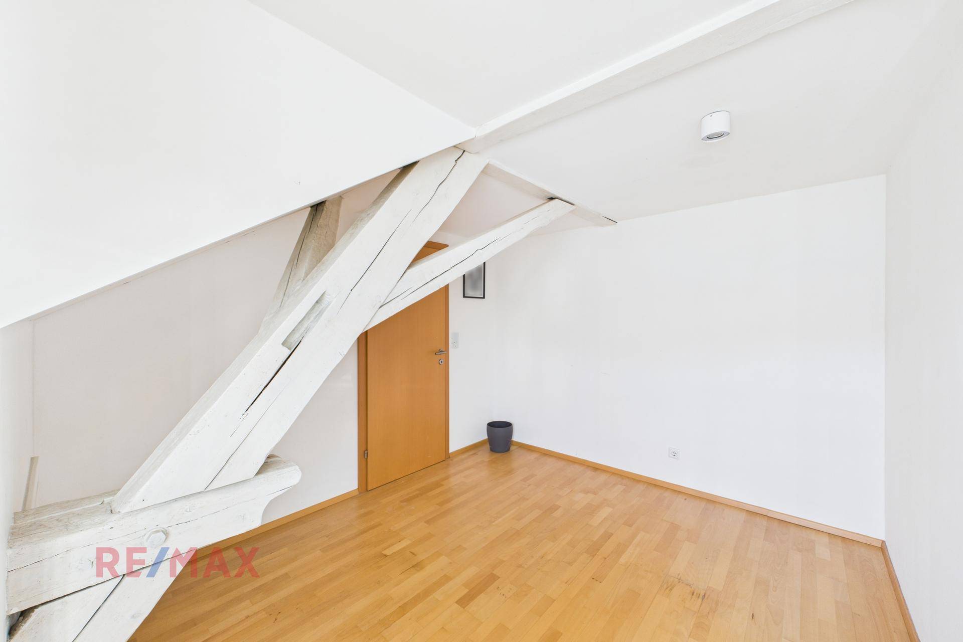 Geräumiges Schlafzimmer im Dachgeschoss mit Holzbalken und Holzboden, hell und offen.