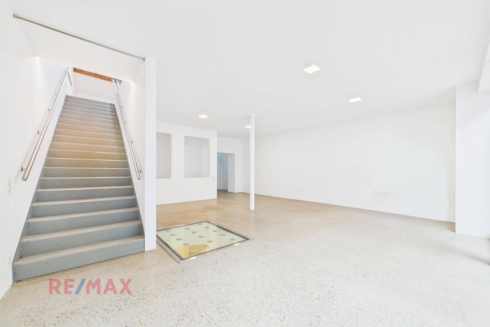 Heller, offener Gewerberaum mit moderner Treppe und Terrazzoboden, ideal für vielfältige Nutzung.