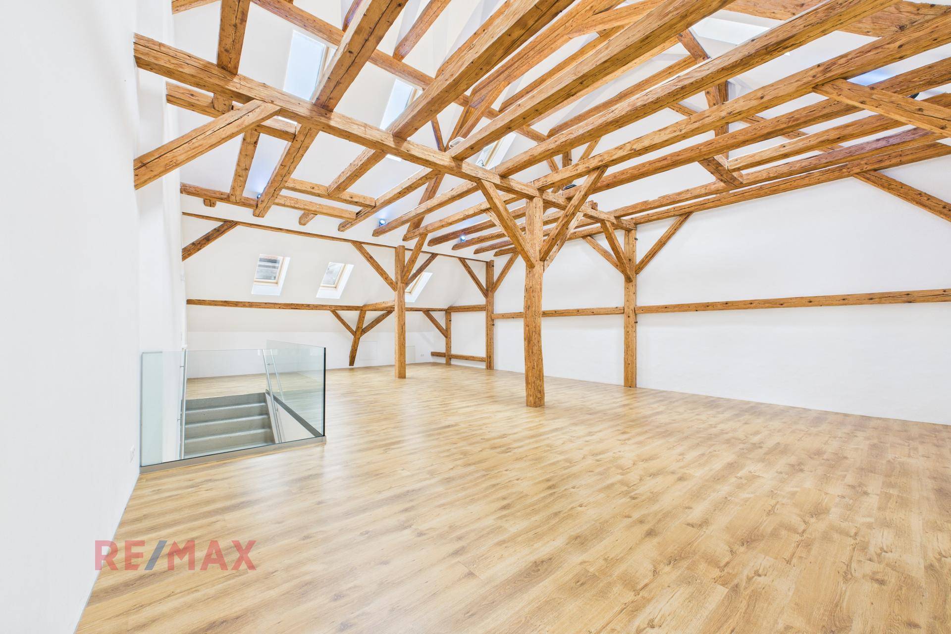 Weitläufiger Dachgeschossraum mit beeindruckenden Holzbalken und hellem Laminatboden.