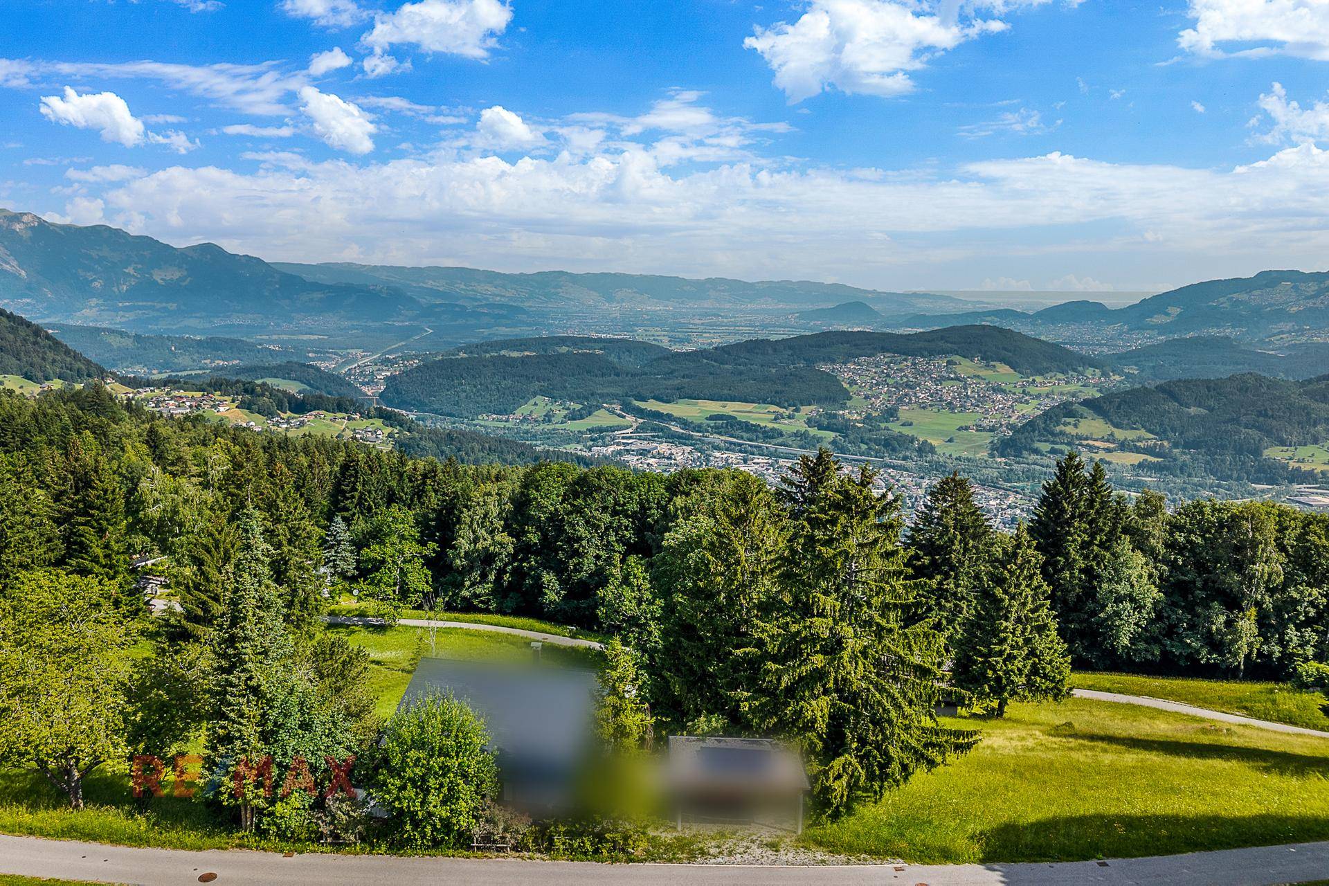 Atemberaubender Ausblick auf eine grüne Landschaft mit einem kleinen Teich und Bergen im Hintergrund.