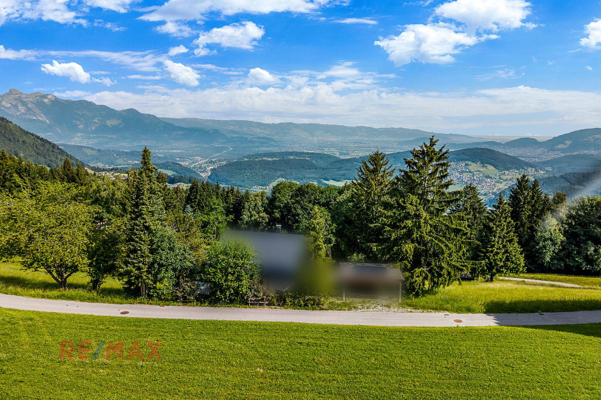 Weitläufiger Panoramablick über grüne Täler und majestätische Berge unter blauem Himmel.
