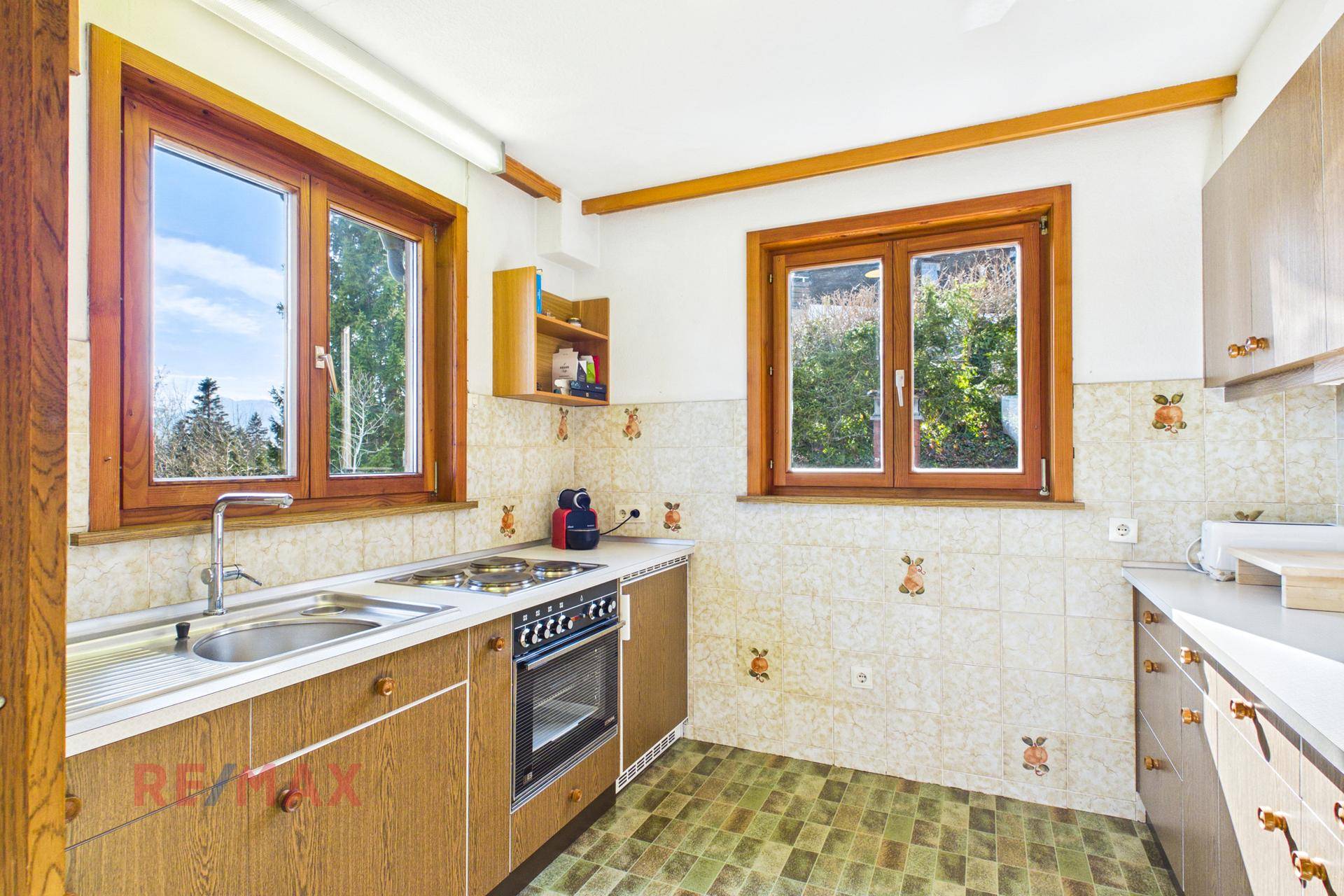 Funktionale Küche mit traditionellen Fliesen, Holzschränken und Fensterblick ins Grüne.