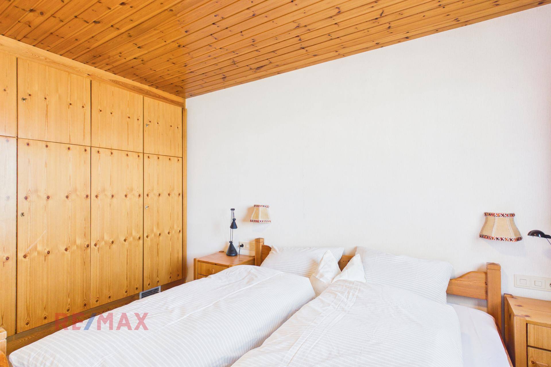 Schlafzimmer mit Holzdecke, Einbauschränken und zwei Einzelbetten.