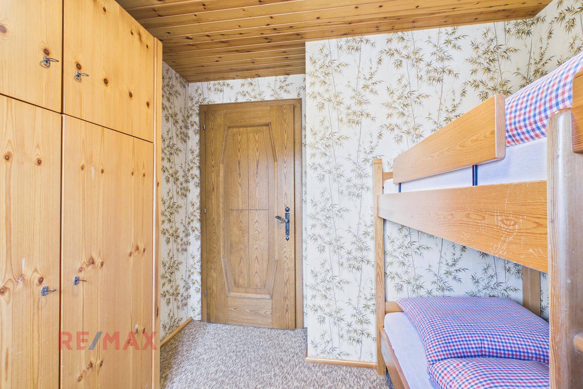 Schlafzimmer mit Etagenbett, Holzschrank und Holztür.