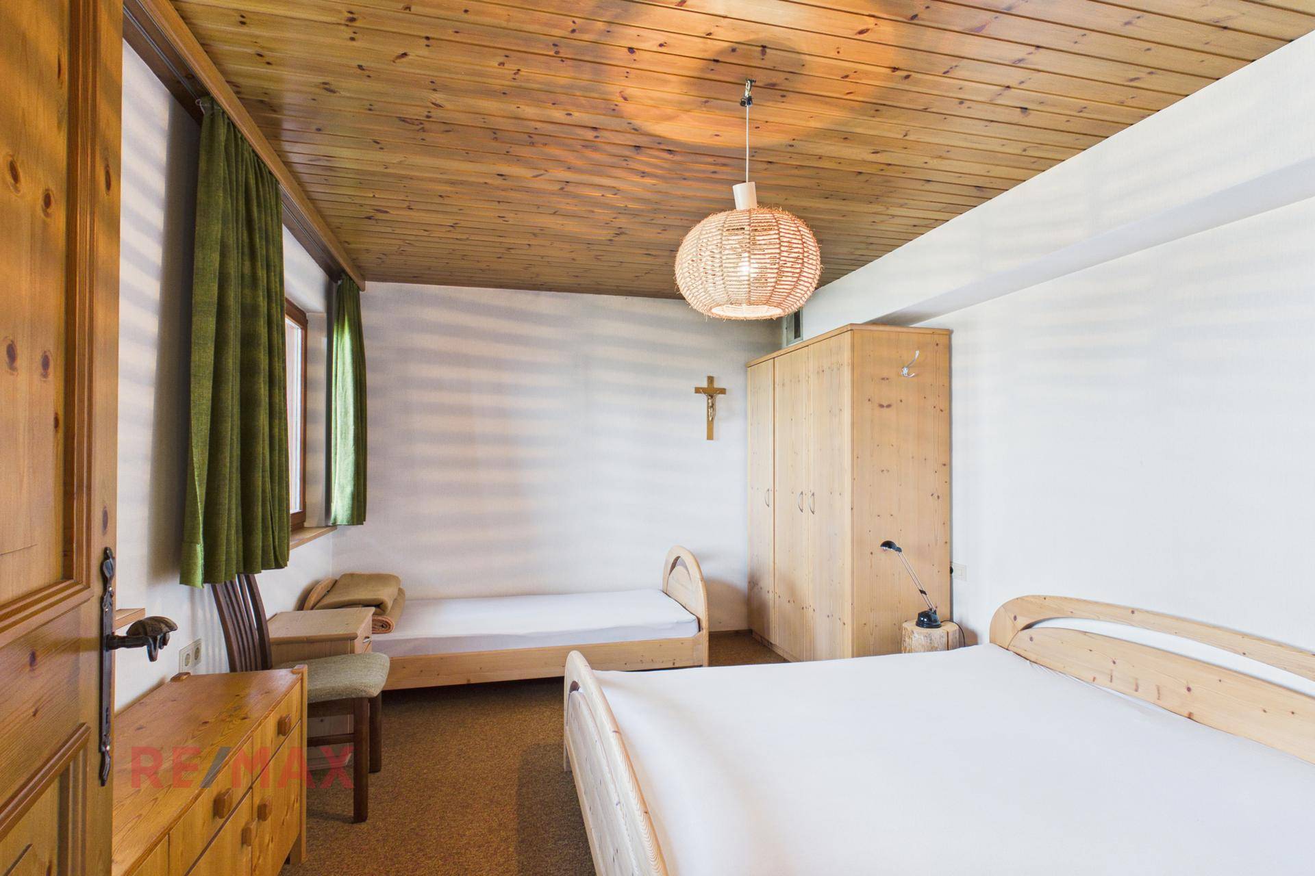 Schlafzimmer mit Einzelbett, Holzschrank und Blick ins Grüne.