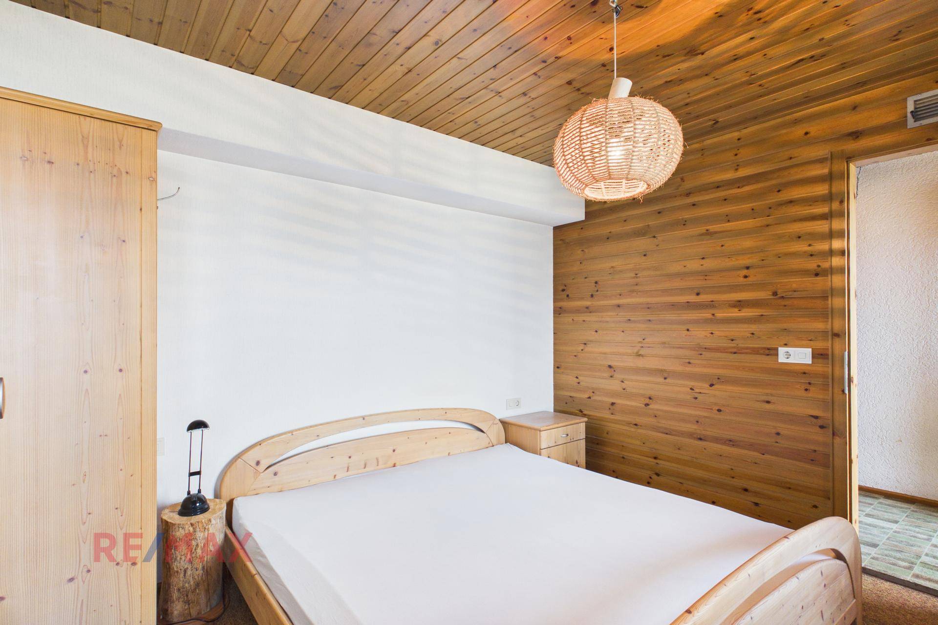 Schlafzimmer mit Doppelbett, Holzvertäfelung und Nachttisch.