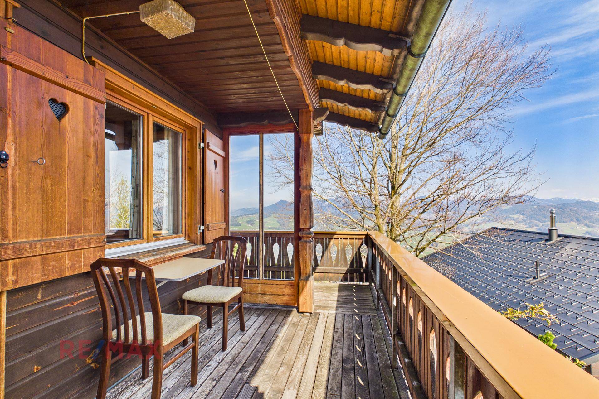 Gemütlicher Holzbalkon mit Sitzgelegenheiten und weitem Blick auf die Berge.