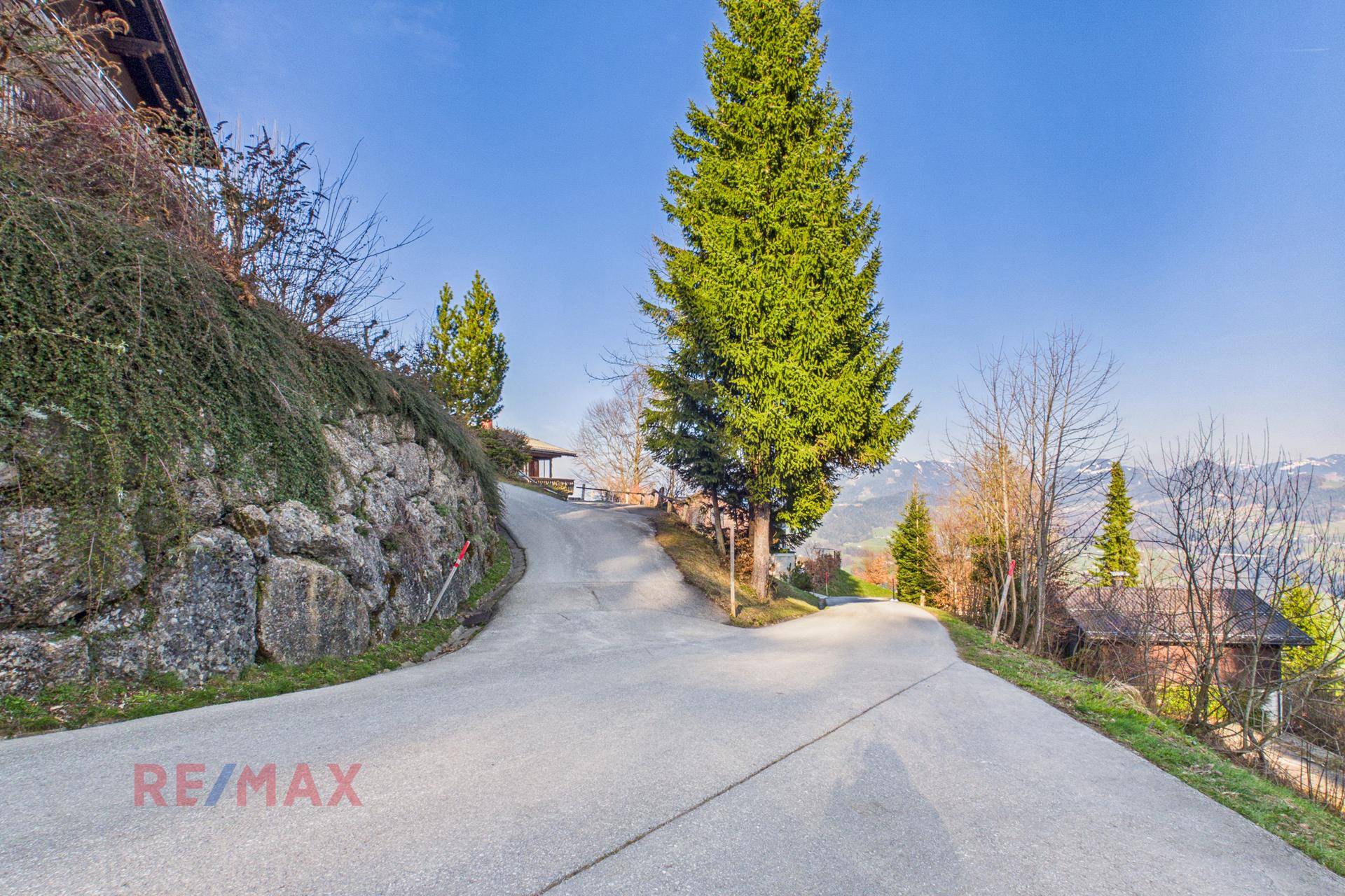Serpentinenstraße führt durch die grüne Landschaft zu den Häusern am Hang.