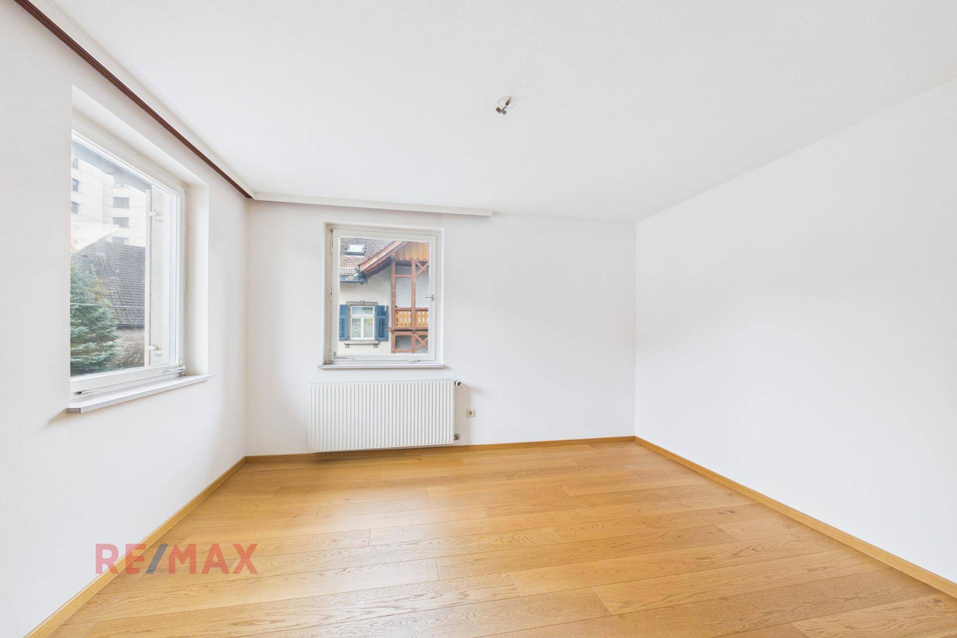 Geräumiges Zimmer mit Parkettboden und zwei Fenstern, die viel Licht spenden.
