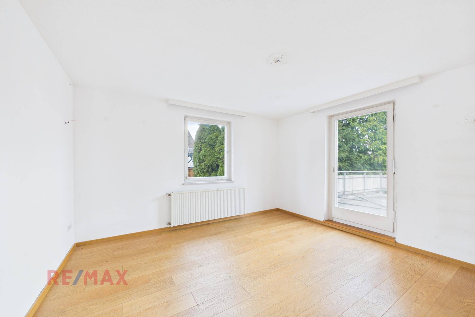 Helles Zimmer mit Parkettboden und direktem Zugang zum Balkon.