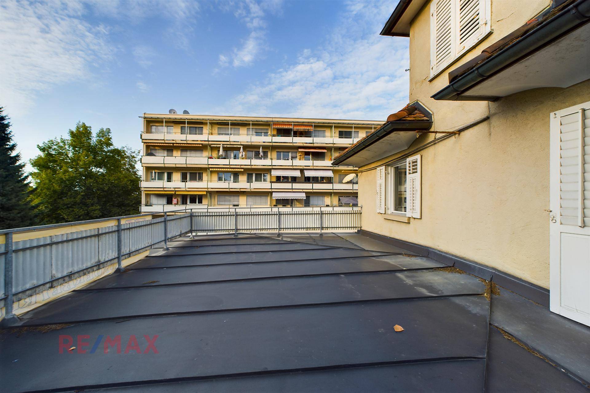 Große Dachterrasse mit Blick auf die umliegenden Gebäude und den Himmel.