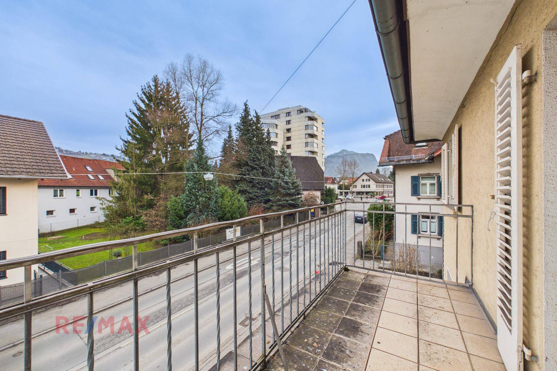 Balkon mit Metallgeländer und Blick auf die Straße und die umliegende Bebauung.