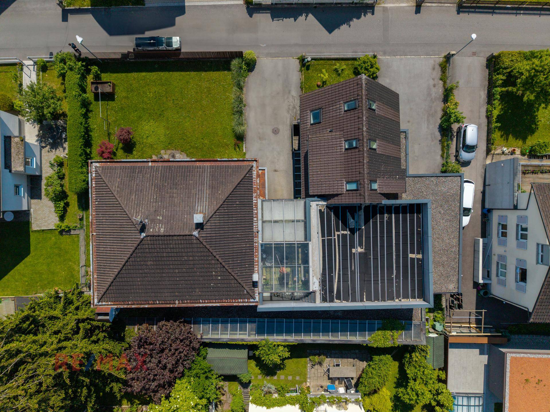 Senkrechte Luftaufnahme von zwei Wohnhäusern mit Dächern, Gärten und angrenzenden Straßen.