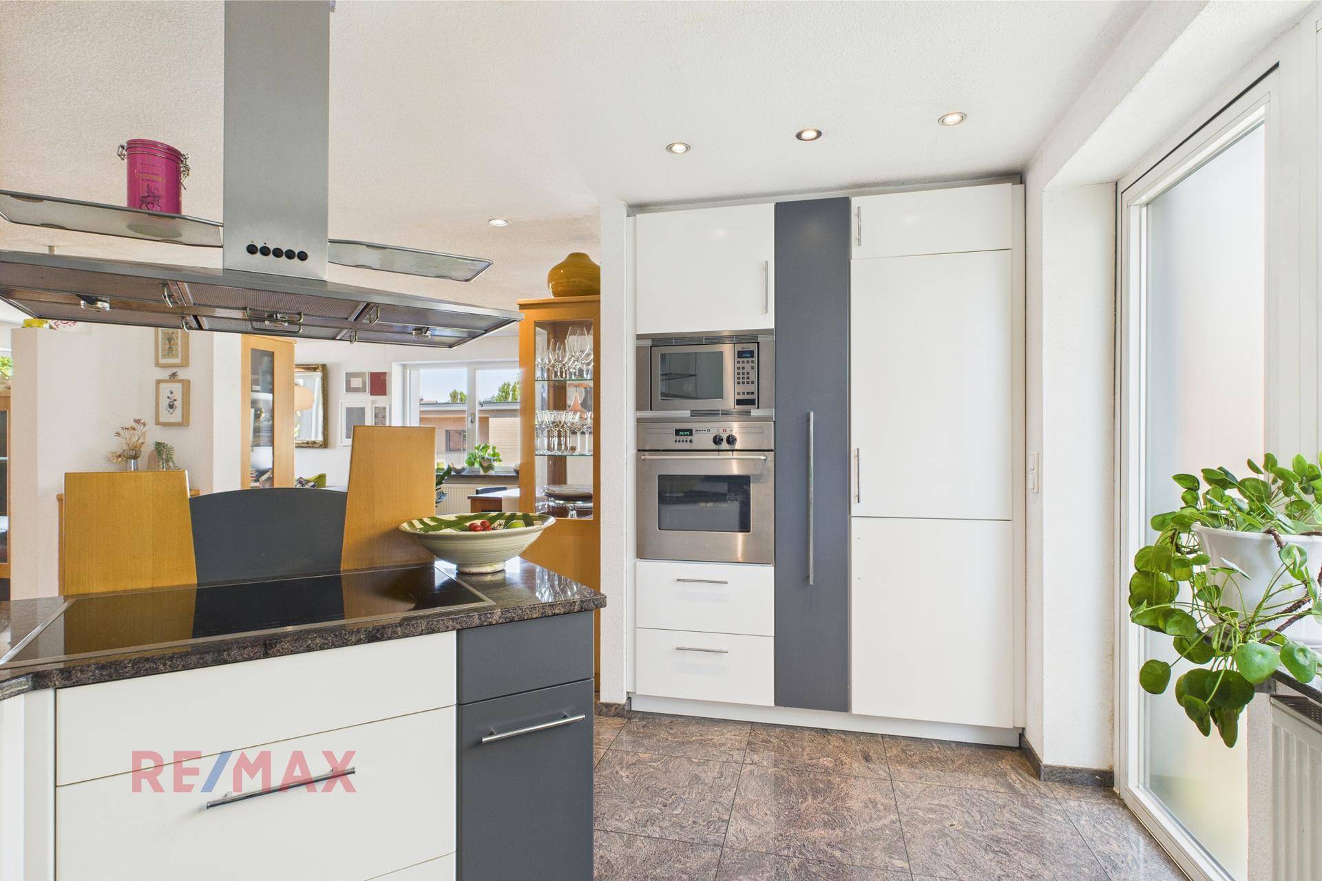 Moderne Küche mit weißen und grauen Schränken, integriertem Backofen und Mikrowelle.