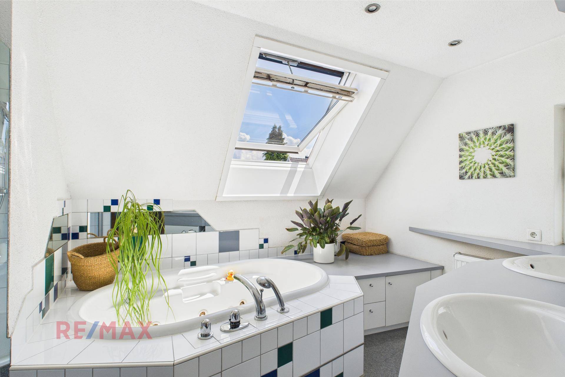 Geräumiges Badezimmer mit Badewanne, Dachfenster und bunten Fliesen an den Wänden.