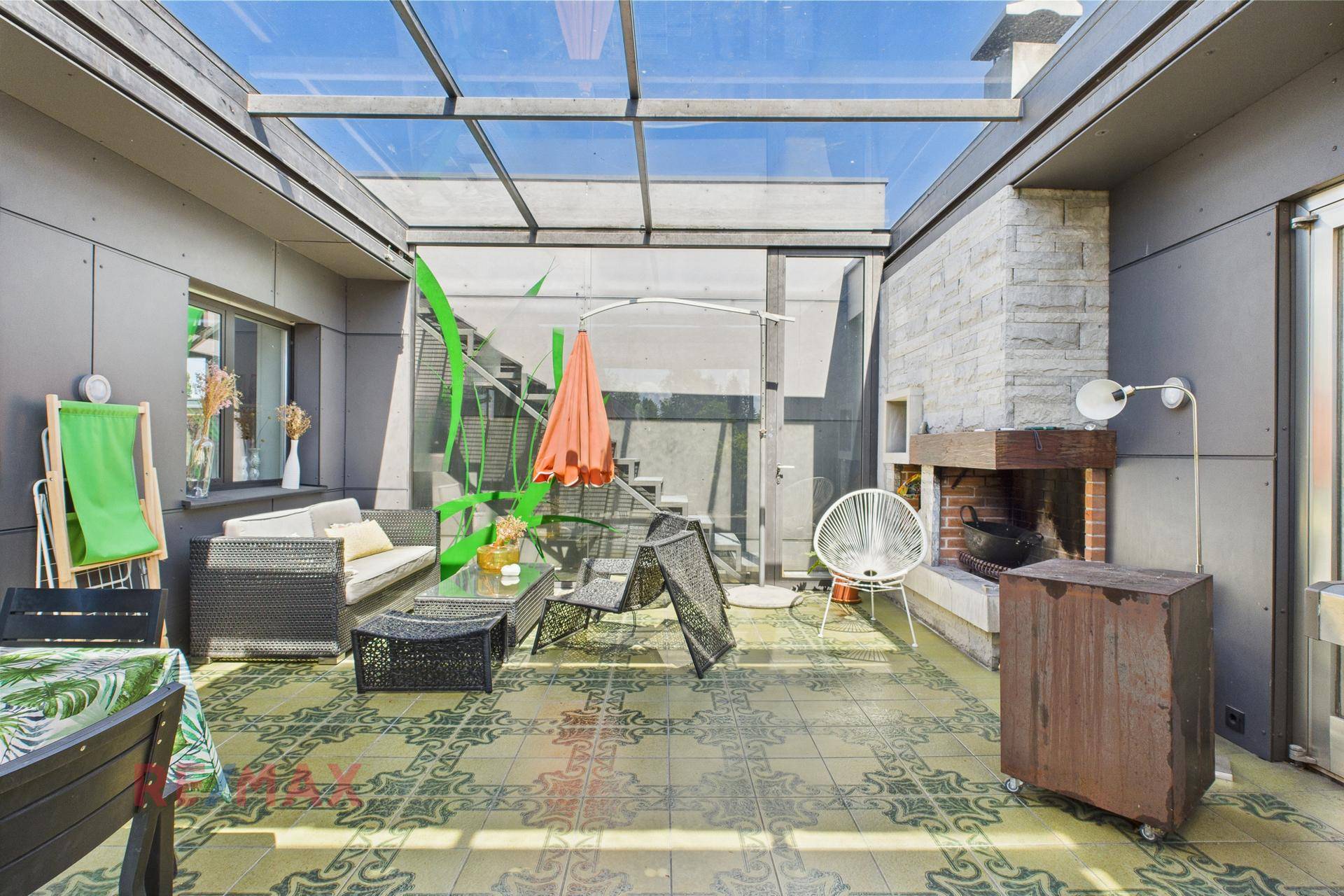 Große überdachte Terrasse mit Sitzmöbeln, Außenkamin und Glasdach für viel Tageslicht.