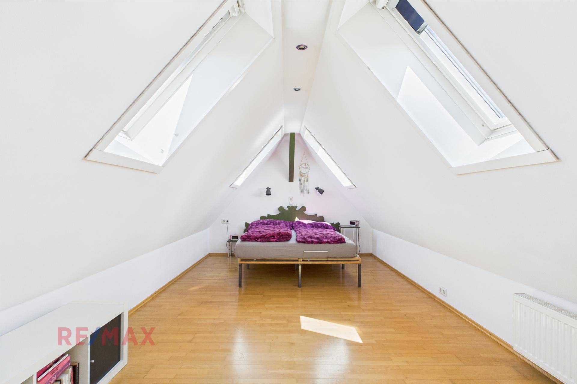 Geräumiges Schlafzimmer im Dachgeschoss mit Holzboden, Doppelbett und zwei großen Dachfenstern.