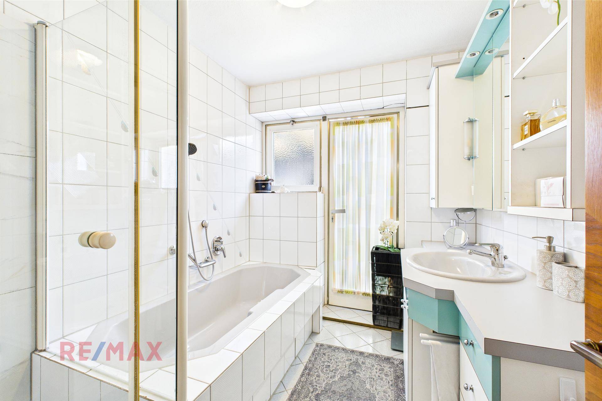 Badezimmer mit Badewanne, Duschabtrennung und Waschbecken mit hellblauen Akzenten.