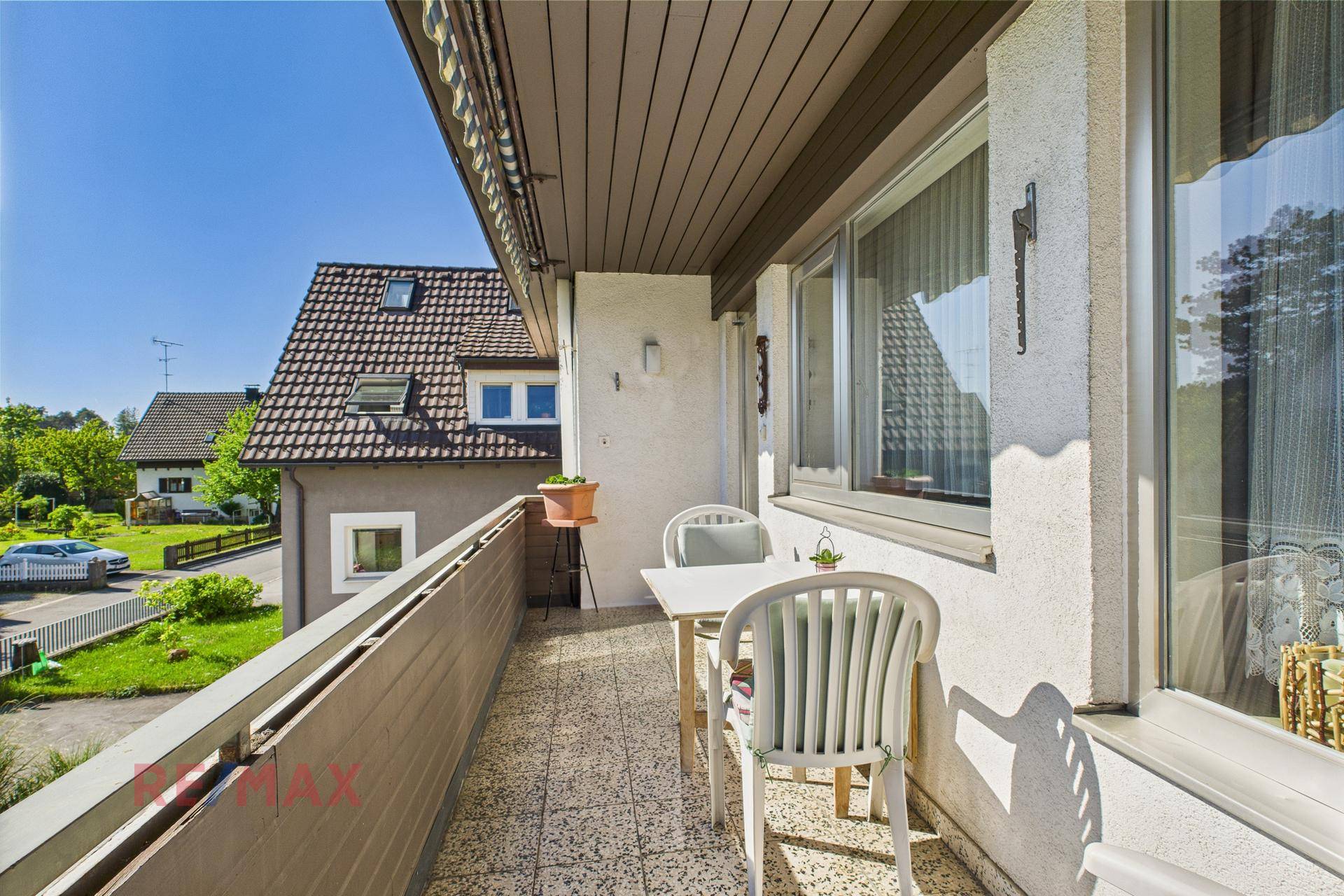 Balkon mit Tisch und Stühlen, Blick auf die Nachbarschaft und viel Sonnenlicht.