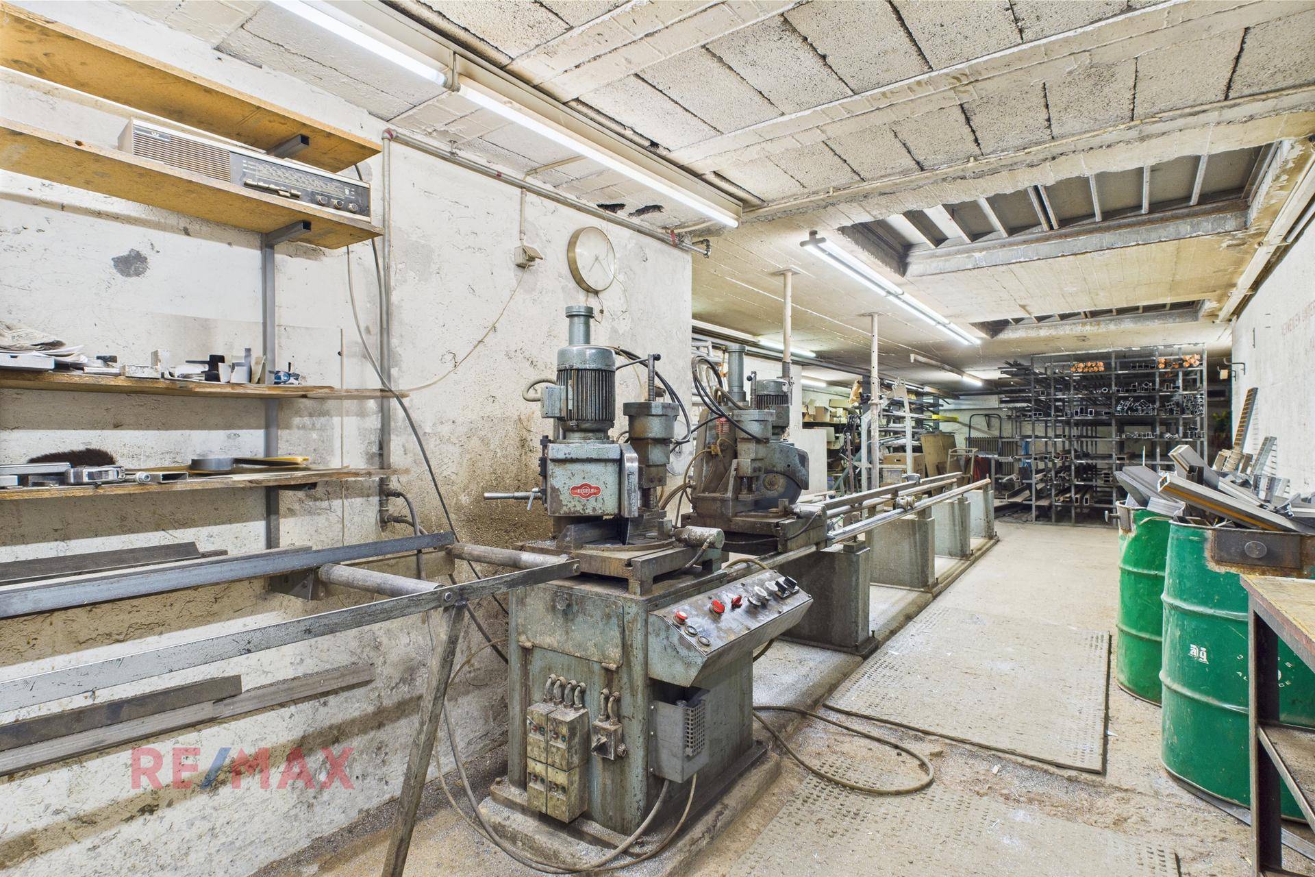 Werkstattbereich mit Maschinen, Werkbänken und industrieller Beleuchtung.