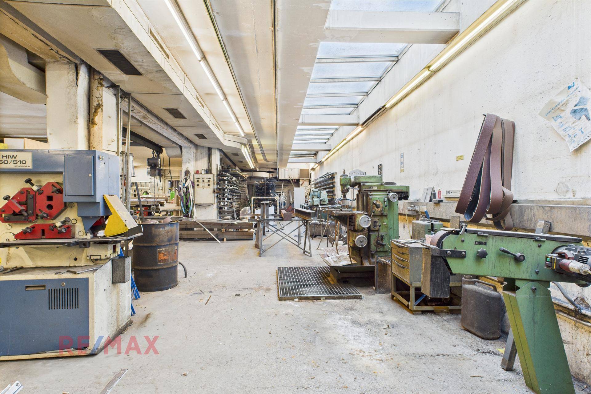 Große Werkstatt mit verschiedenen Maschinen, Werkzeugen und Tageslicht durch Oberlichter.