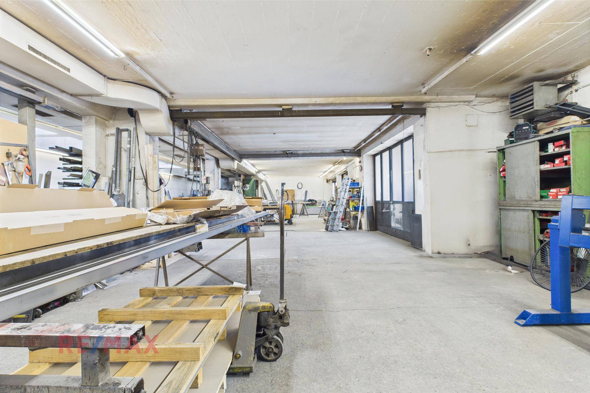 Geräumige Werkstatt mit Arbeitsbereichen, Lagerflächen und Zugang nach draußen.