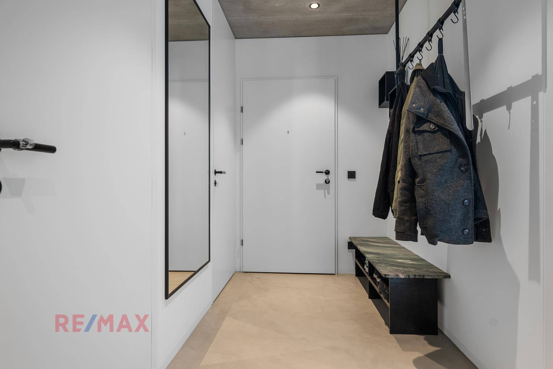 Heller Eingangsbereich mit Garderobe, großem Spiegel und minimalistischer Gestaltung.