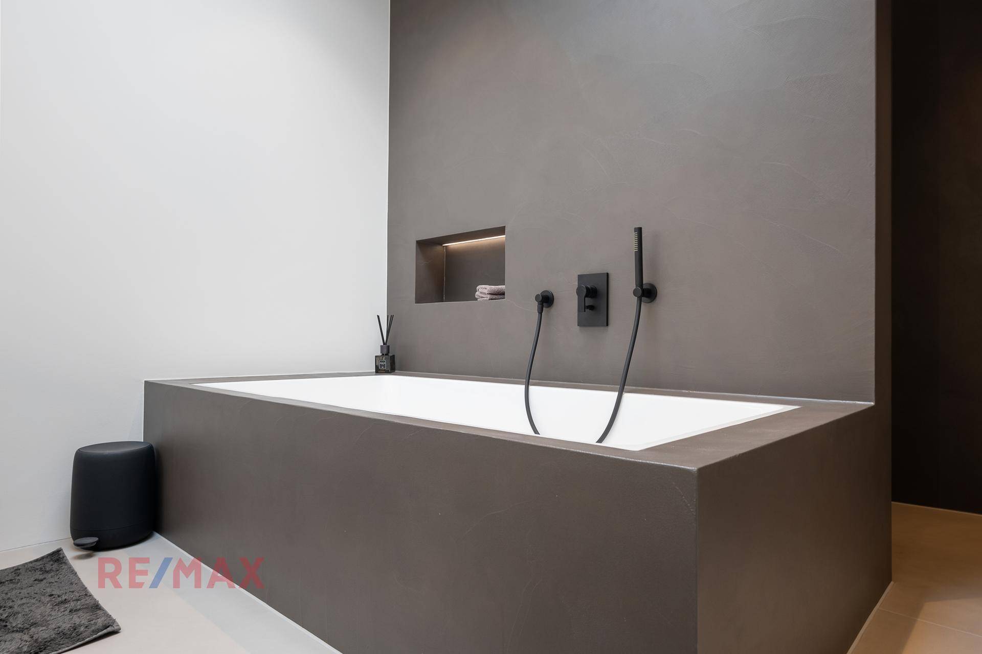 Elegante Badewanne in modernem Badezimmer mit minimalistischem Design und grauen Wänden.