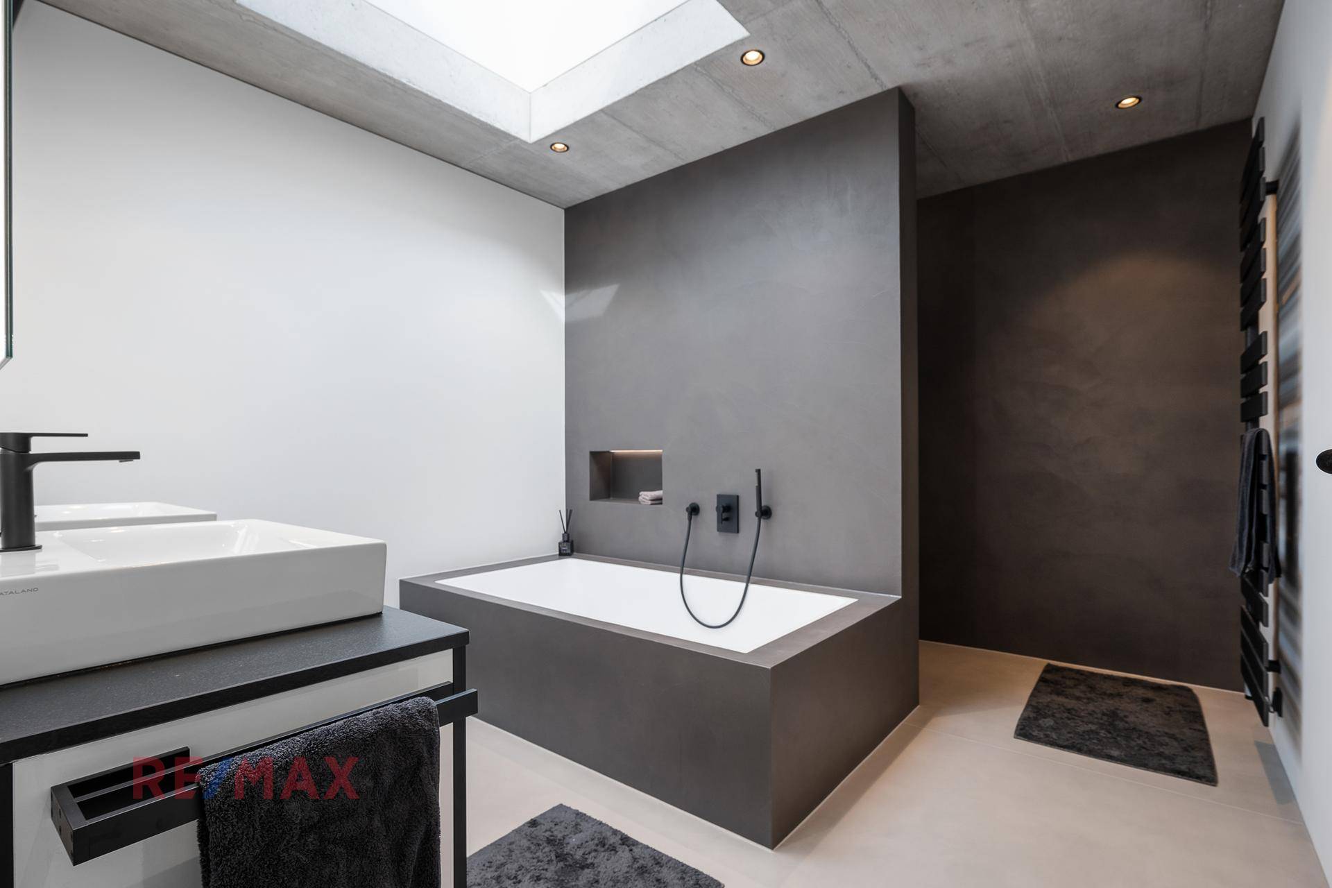 Modernes Badezimmer mit Badewanne, Doppelwaschbecken, Oberlicht und beheiztem Handtuchhalter.