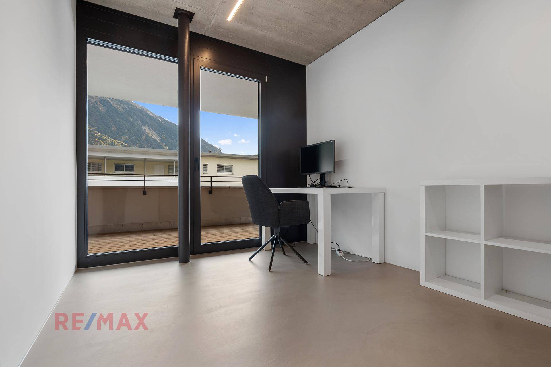 Arbeitszimmer mit viel Tageslicht und Blick auf die umliegende Berglandschaft vom Balkon.