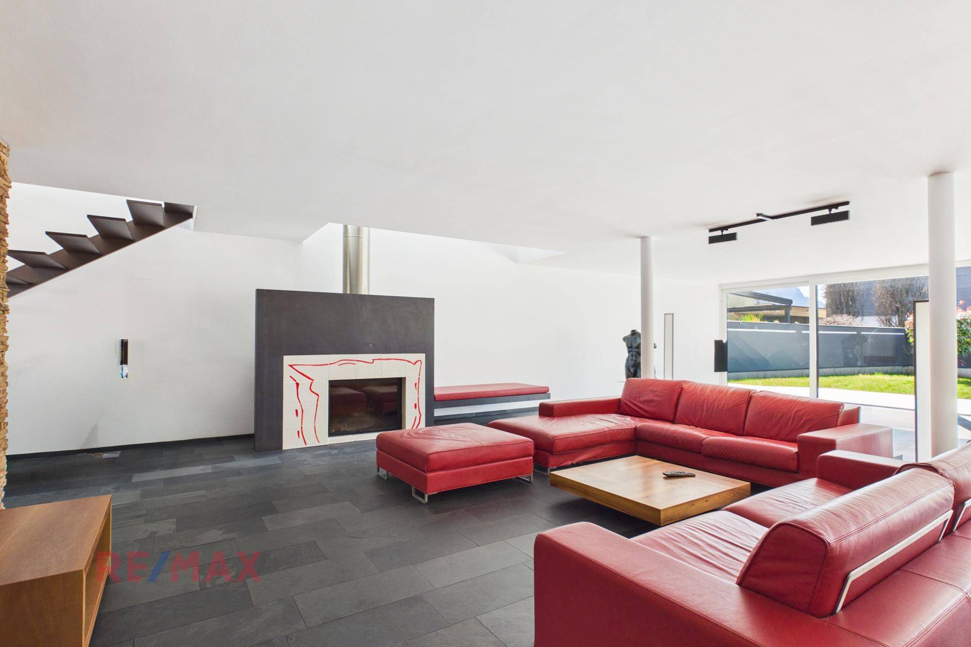 Modernes Wohnzimmer mit Kamin, roten Ledersofas und Zugang zum Garten.