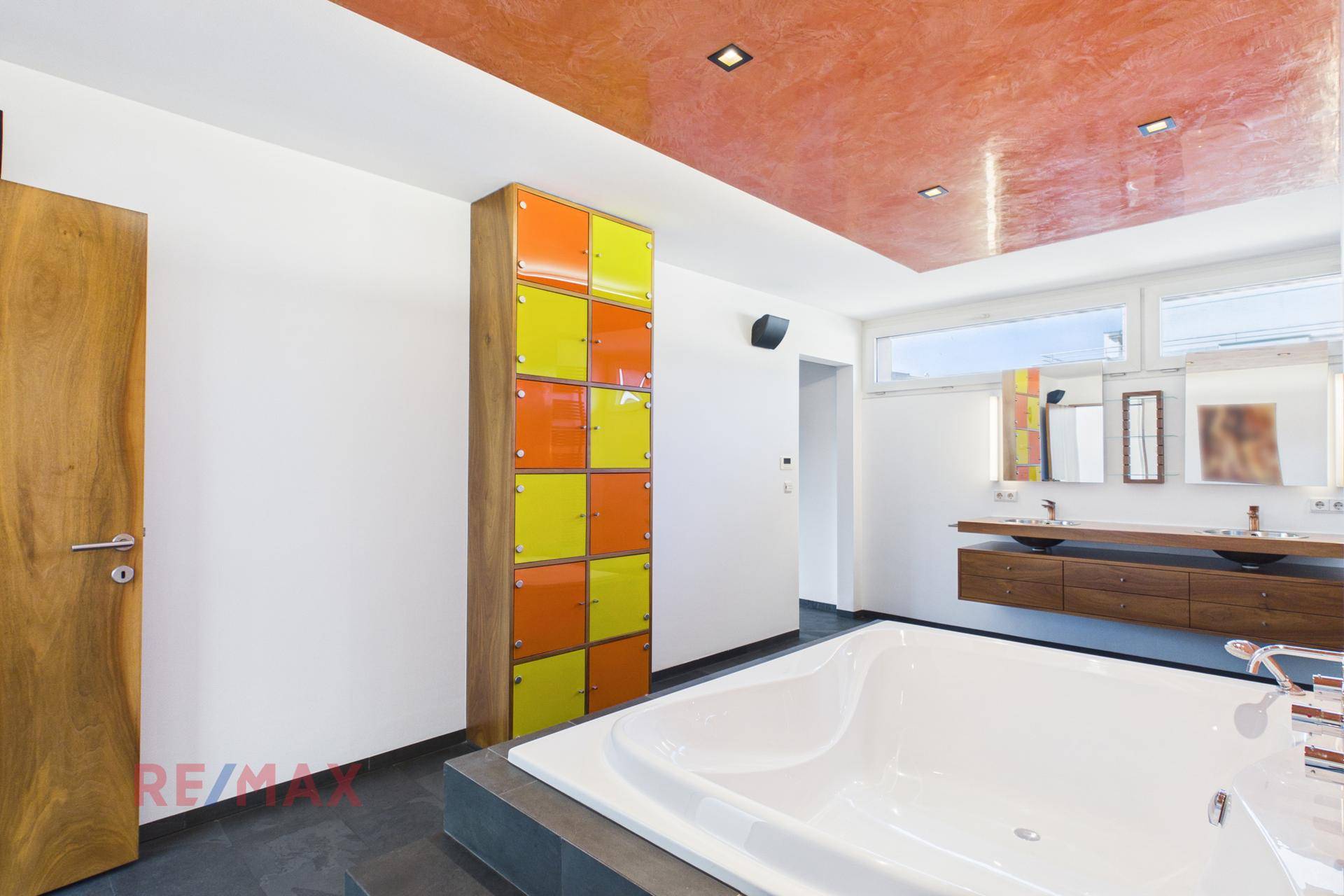 Geräumiges Badezimmer mit eingelassener Badewanne und farbenfrohen Schränken.