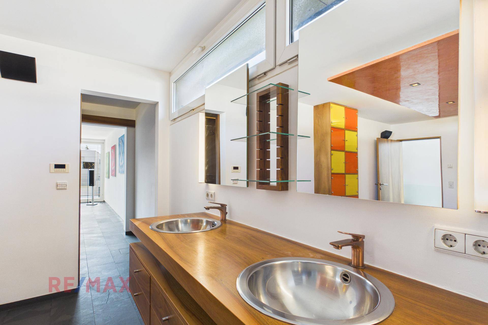 Modernes Badezimmer mit Doppelwaschbecken, Holzunterschrank und großem Spiegel.
