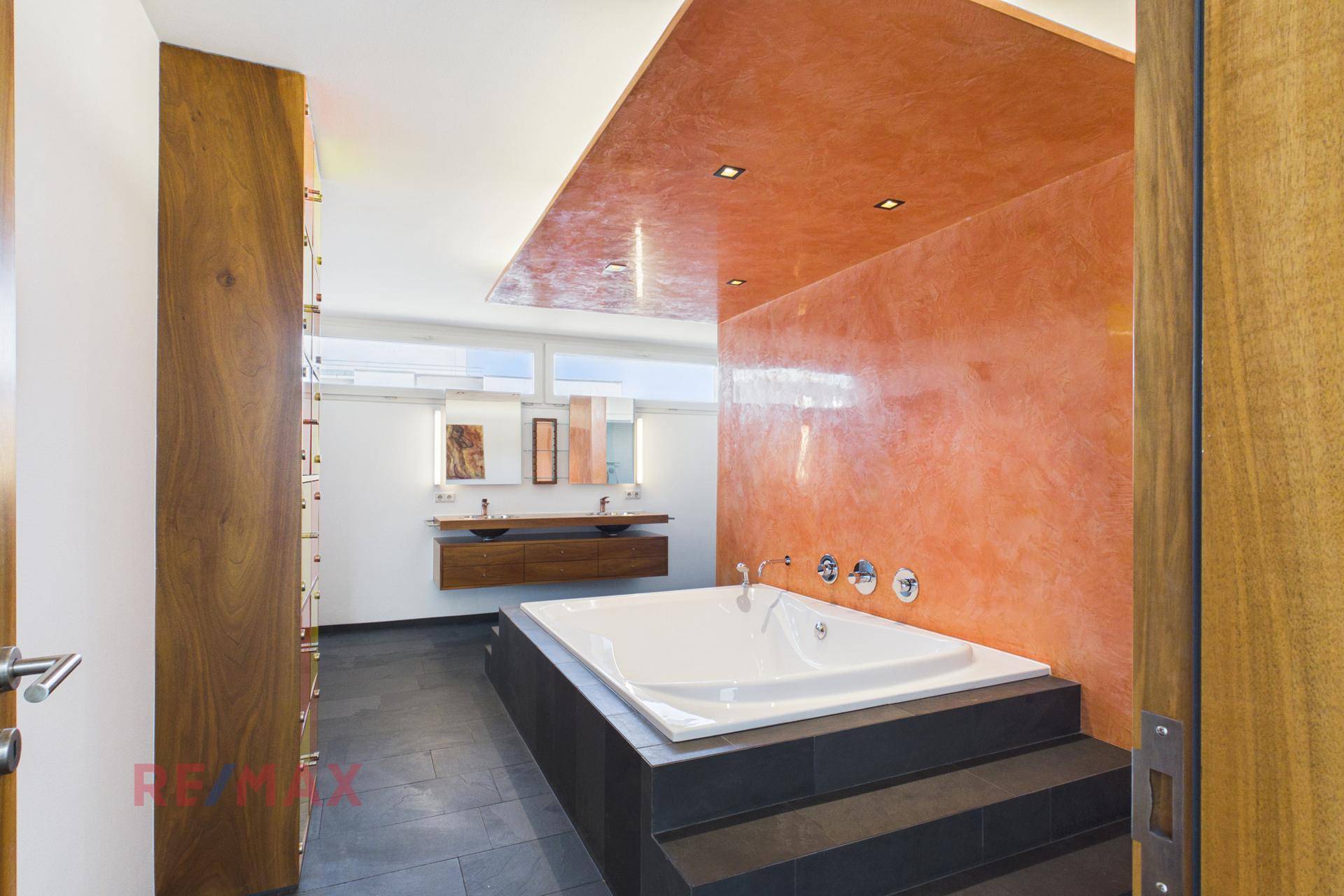 Elegantes Badezimmer mit großer Badewanne, Doppelwaschbecken und moderner Wandgestaltung.