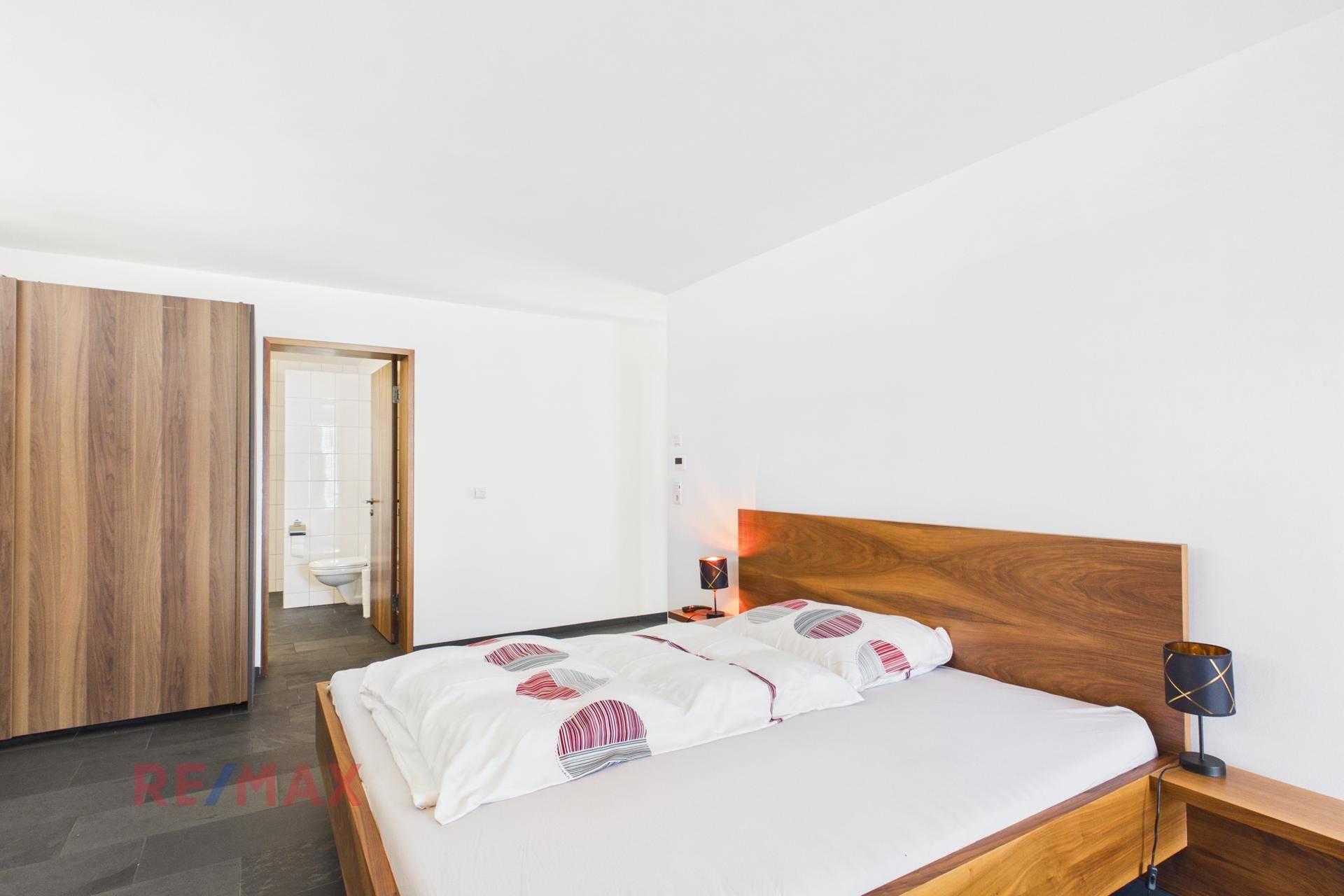 Gemütliches Schlafzimmer mit Doppelbett, Holzschrank und Zugang zum Badezimmer.