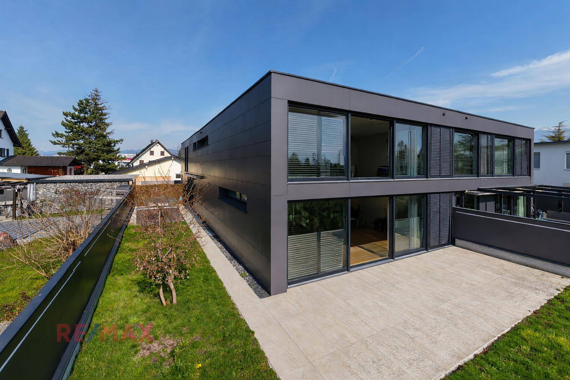 Moderne Architektur eines Wohnhauses mit großen Fenstern und gepflegtem Garten.