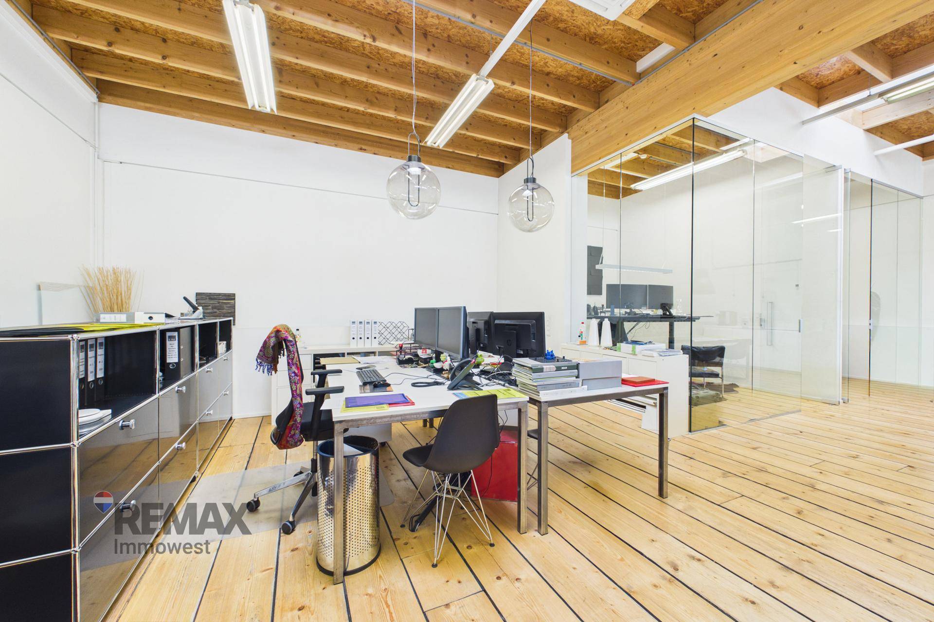 Geräumiges Büro mit mehreren Arbeitsplätzen, Holzboden und hohen Decken.