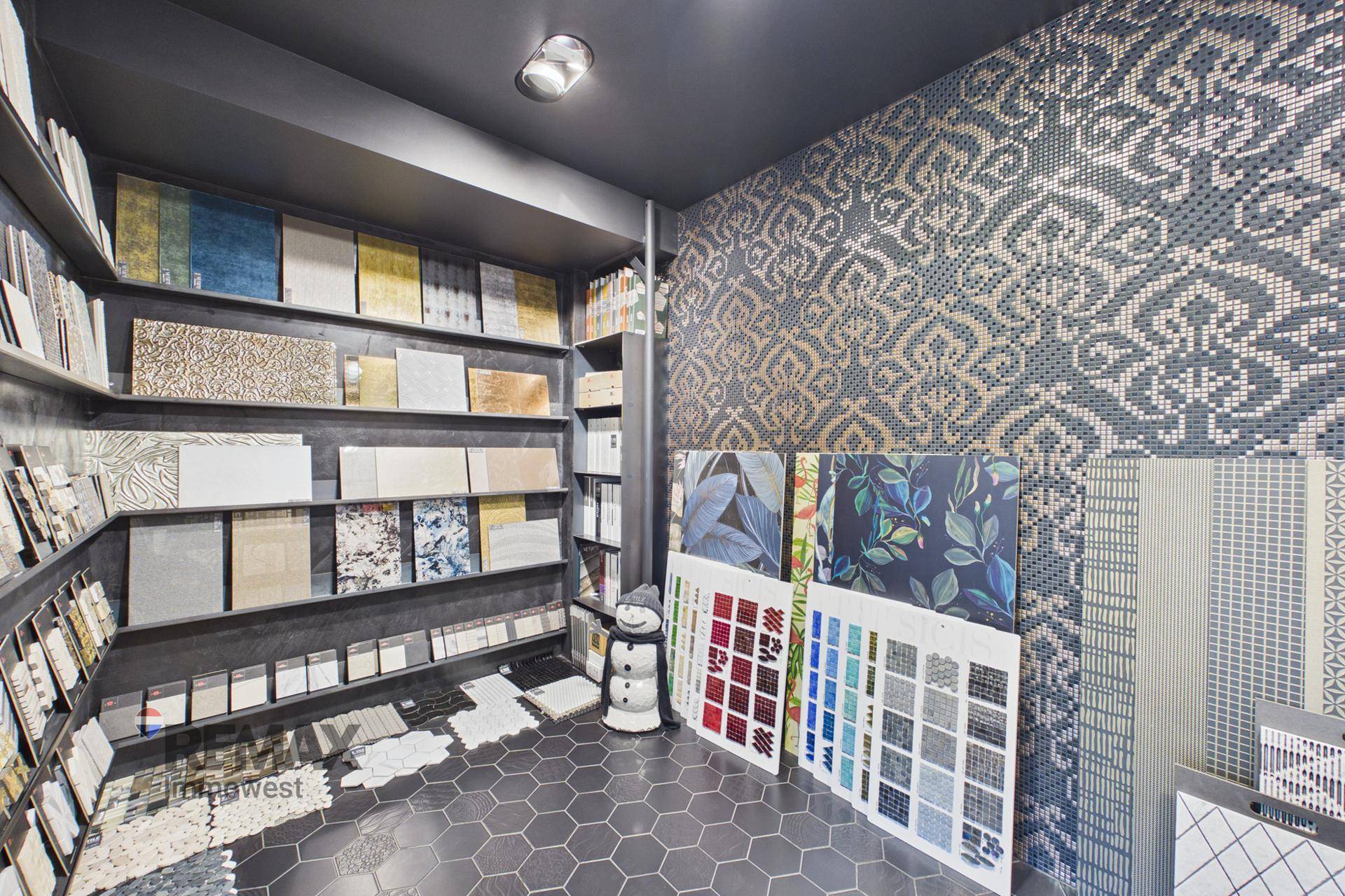 Kreativer Ausstellungsbereich mit gemusterten Wand- und Bodenfliesen in dunklerer Atmosphäre.