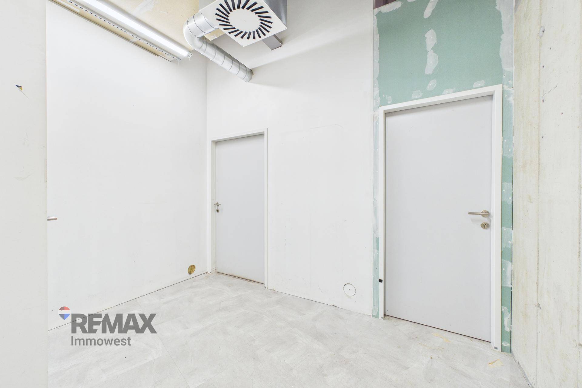 Kleiner Raum mit zwei Türen, weißen Wänden und sichtbaren Deckeninstallationen, ideal als Abstell- oder Technikraum.